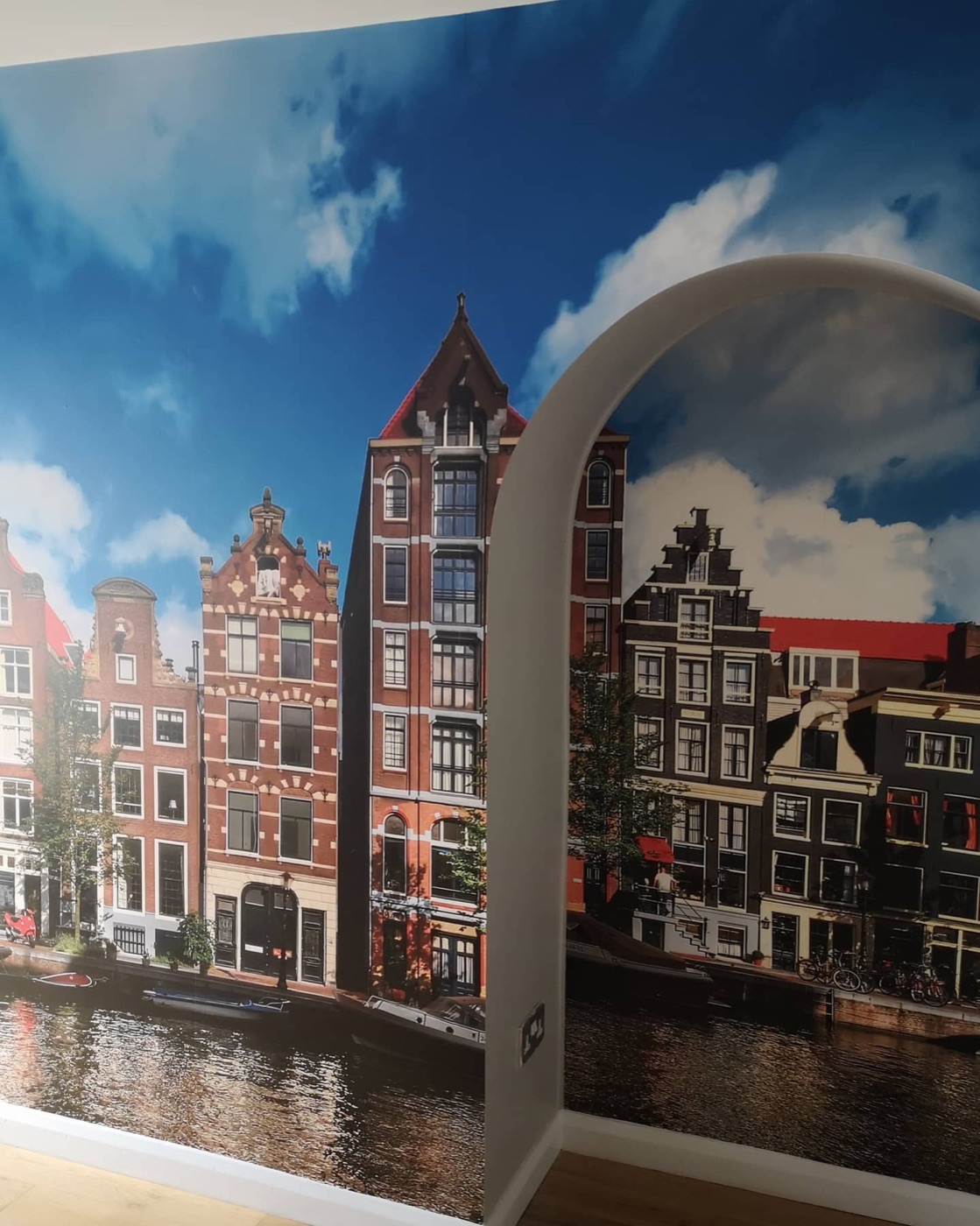 A feature wall mural of Amsterdam canal houses seen through an arched alcove